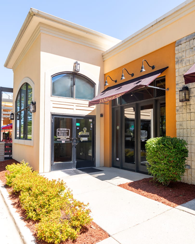 Exterior of Nonnie's restaurant with a "Sandwiches" awning and visible operating hours on the door.