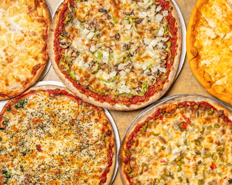 Five delicious pizzas with various toppings, including pineapple, vegetables, and cheese.