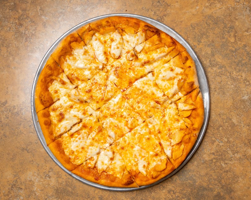 A whole cheese pizza, cut into square slices, on a metal pan.
